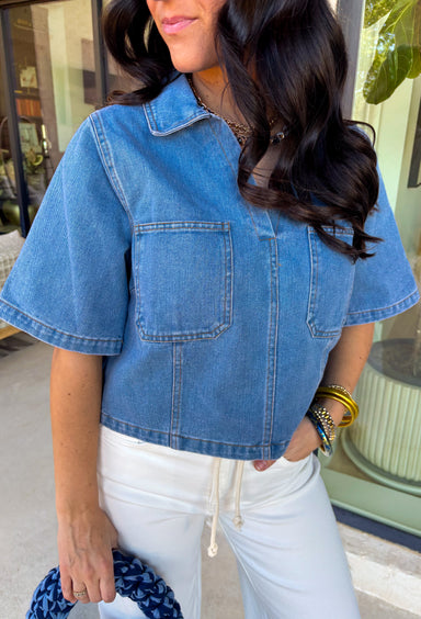 This medium wash denim top is giving effortless spring style in the best way. With its crisp collared neckline, short sleeves, and cropped length, it’s the kind of piece you can throw on and instantly look put together. The chest pockets add that classic denim touch, making it perfect for pairing with high-rise jeans, shorts, or a cute flowy skirt for an easy warm-weather outfit.