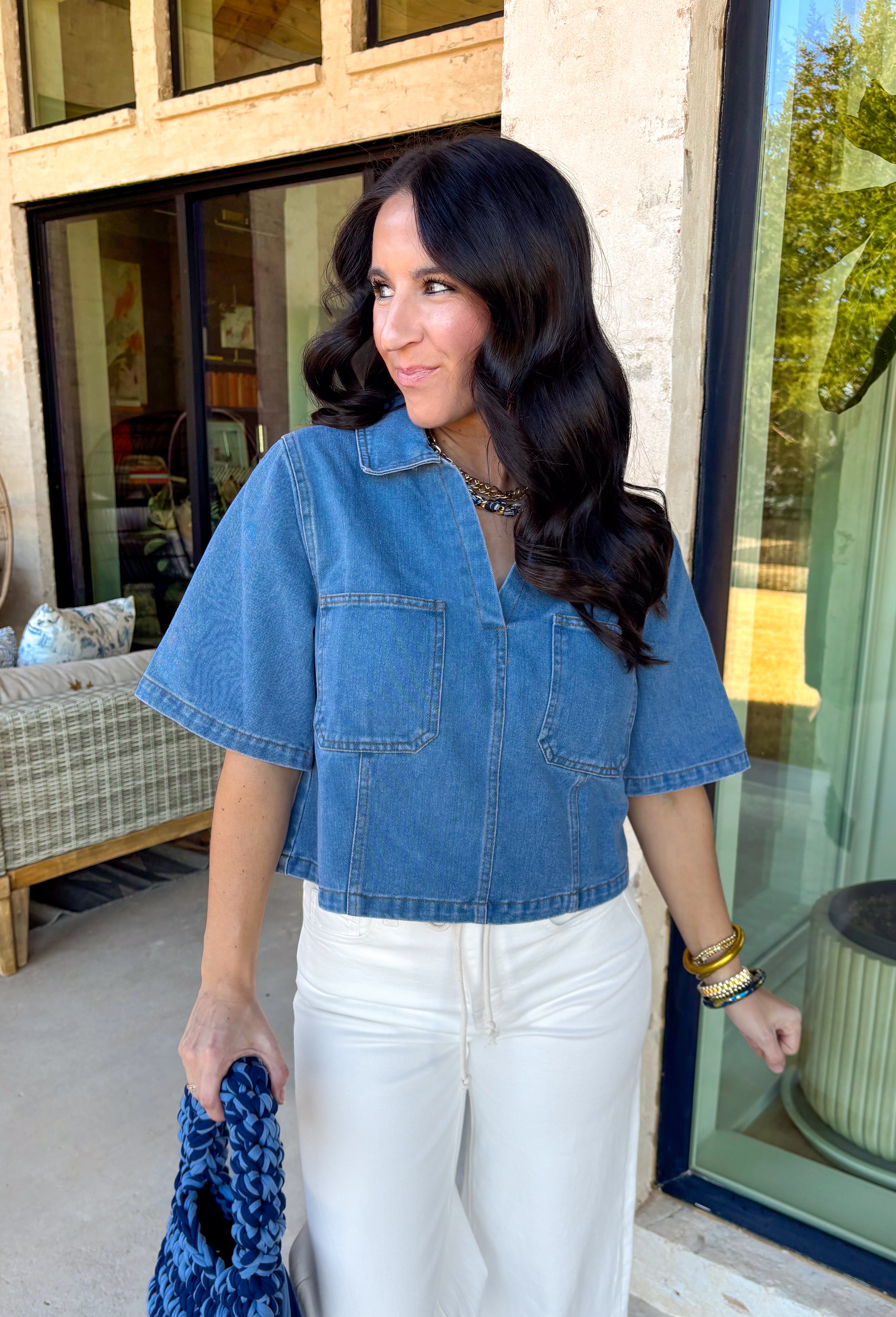 This medium wash denim top is giving effortless spring style in the best way. With its crisp collared neckline, short sleeves, and cropped length, it’s the kind of piece you can throw on and instantly look put together. The chest pockets add that classic denim touch, making it perfect for pairing with high-rise jeans, shorts, or a cute flowy skirt for an easy warm-weather outfit.