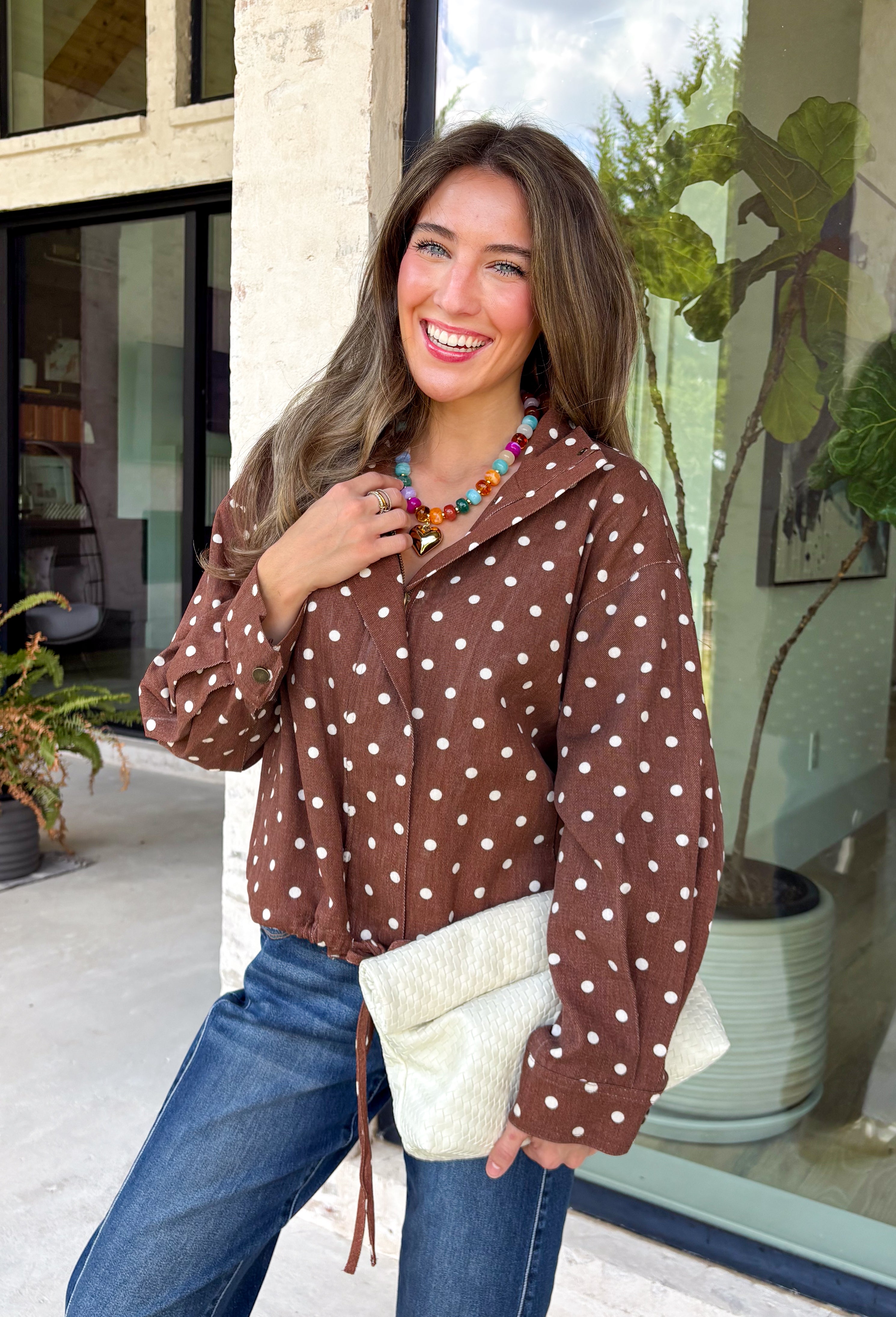 Give your layering collection a playful update with this charming denim jacket from Entro. Crafted from classic brown denim with a timeless off-white polka dot print, this versatile jacket is the perfect finishing touch for all your fall outfits. The collared neckline and front zipper closure create a classic look, while the adjustable drawstring hem lets you customize the fit.