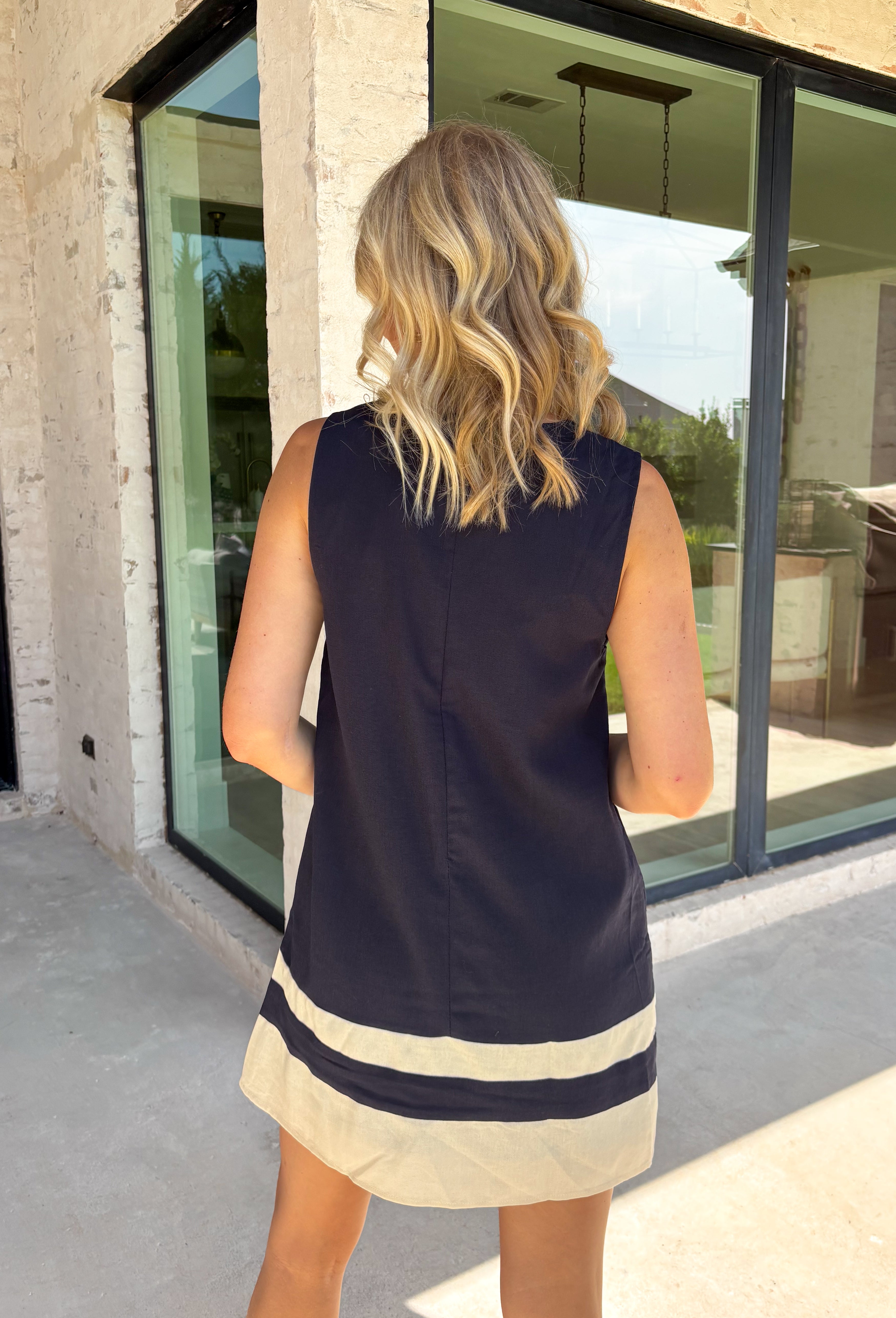 This navy dress is the perfect blend of timeless charm and fall-ready style! Delicate cream floral embroidery adds a beautiful handcrafted touch, while the matching contrast hem creates a polished finish that makes this dress stand out. Designed with a flattering sleeveless silhouette, back zipper closure, and side pockets (because we know they're a favorite!), it's as practical as it is stylish. 