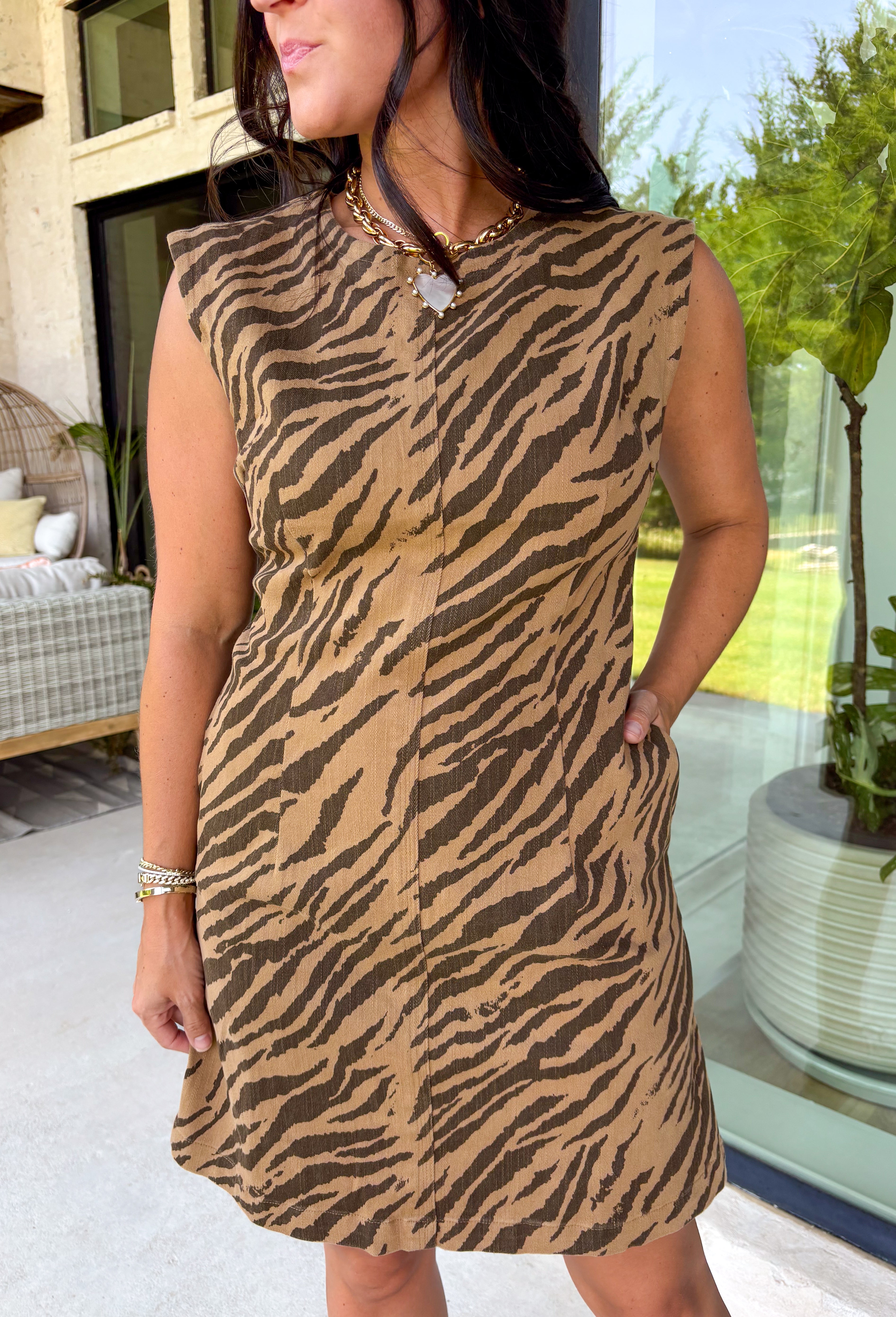 Make a statement this season with this effortlessly chic denim zebra print dress. Designed in a rich brown hue with a timeless zebra print, this sleeveless style is the perfect blend of bold and sophisticated. The shoulder detailing adds a modern touch, while the structured silhouette creates an effortlessly polished look.