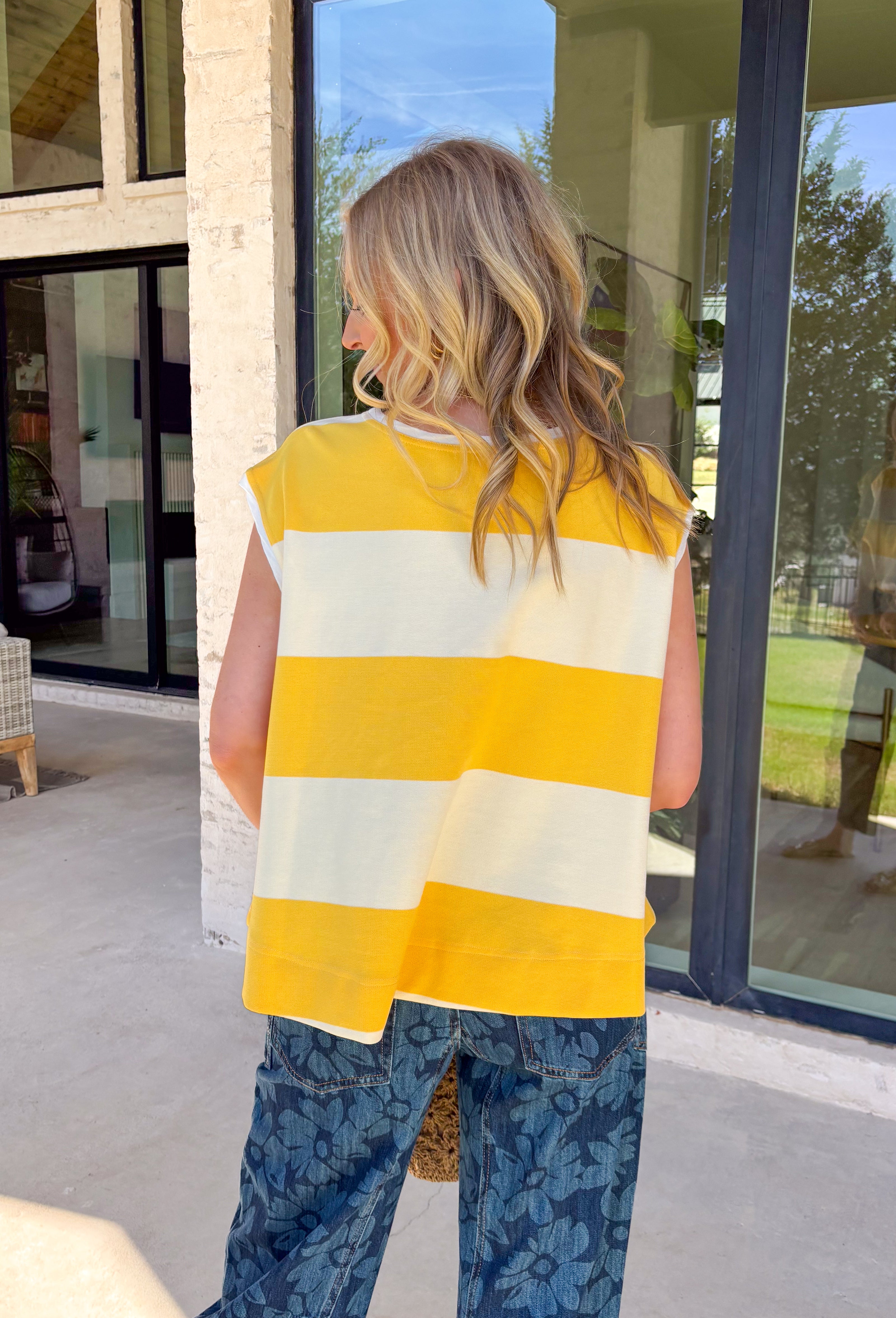 This sleeveless off white and yellow striped top by Wishlist is the perfect little piece to brighten up your spring wardrobe! The bold stripe pattern feels fresh and cheerful, and the sleeveless cut makes it an easy grab for warm days, weekend plans, or layering under a light jacket when the mornings are still a little chilly. Lightweight and easy to style, this top pairs perfectly with denim shorts, white jeans, or a cute skirt for a simple outfit that still feels fun and put-together. 