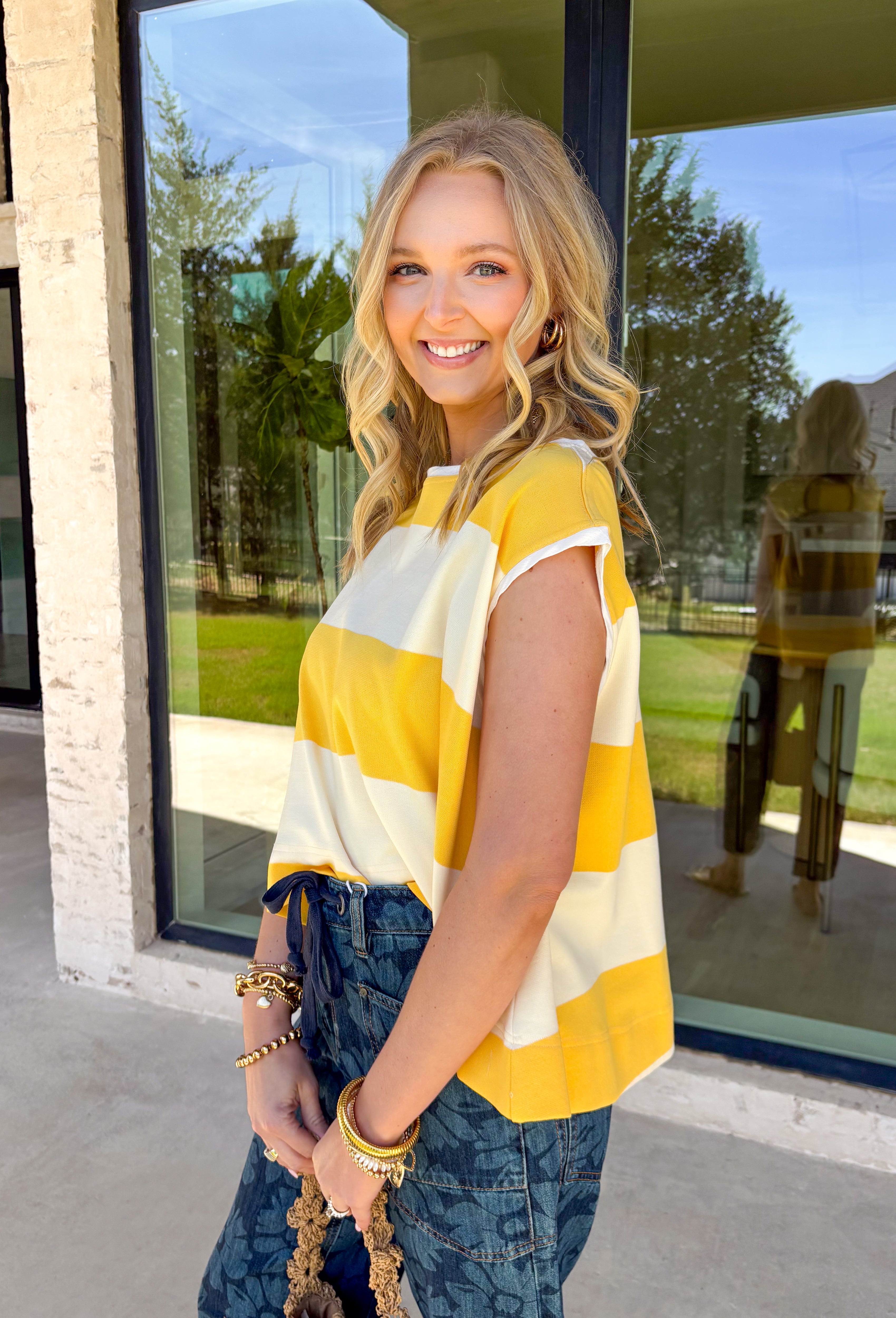 This sleeveless off white and yellow striped top by Wishlist is the perfect little piece to brighten up your spring wardrobe! The bold stripe pattern feels fresh and cheerful, and the sleeveless cut makes it an easy grab for warm days, weekend plans, or layering under a light jacket when the mornings are still a little chilly. Lightweight and easy to style, this top pairs perfectly with denim shorts, white jeans, or a cute skirt for a simple outfit that still feels fun and put-together. 