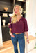 Best Effort Blouse in Merlot, quarter sleeve blouse with ruffle detail around the neck and on the shoulders, v-neck line, ruffling on the bottom of the sleeves 