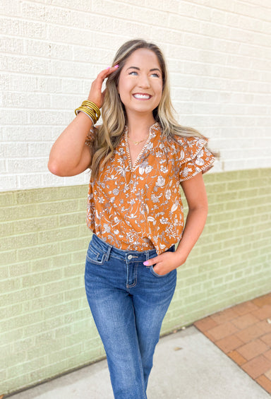 Calling Again Floral Blouse, mustard ruffle sleeve blouse with v-neck and off white floral print, off white whip stitching on the hem of the ruffles on the sleeves, and on the neck line