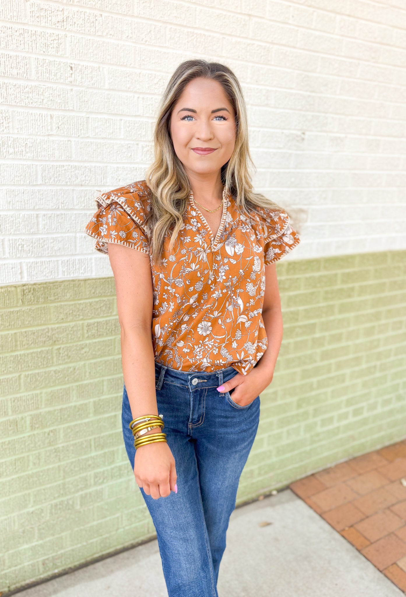 Calling Again Floral Blouse, mustard ruffle sleeve blouse with v-neck and off white floral print, off white whip stitching on the hem of the ruffles on the sleeves, and on the neck line