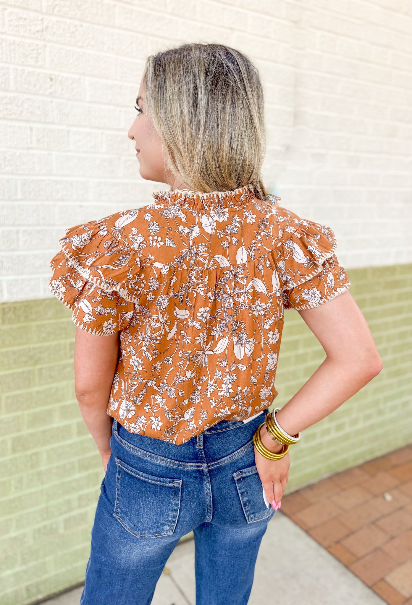 Calling Again Floral Blouse, mustard ruffle sleeve blouse with v-neck and off white floral print, off white whip stitching on the hem of the ruffles on the sleeves, and on the neck line