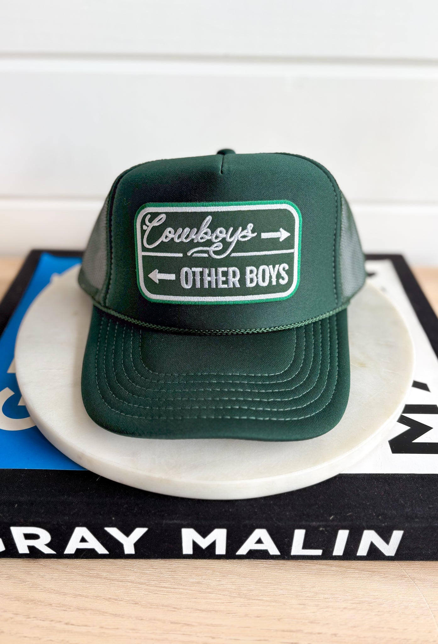 Cowboys & Other Boys Trucker Hat, forest green trucker hat with forest green and kelly green patch in the center of the hat with white embroidered text "cowboys -> other boys <-"