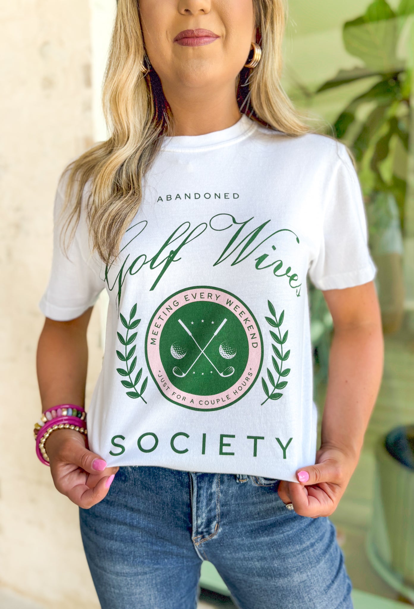 Friday + Saturday: Golf Wives T-Shirt, white t-shirt with kelly green text "abandoned golf wives society" with pink and kelly green golf club emblem 