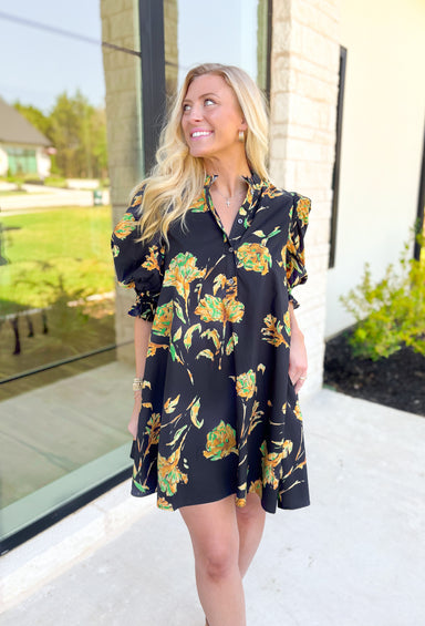 Glimpse Of Us Floral Dress, black, yellow, and green floral quarter button down puff sleeve dress with pleating on the collar and sleeves, tie detail on the back of the dress 