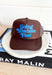 Going Nowhere Fast Trucker Hat in Brown, brown trucker hat with blue text "going nowhere fast" in the center 