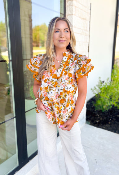 Good Times Floral Blouse, short ruffle sleeved floral blouse in the colors mustard, yellow, white, olive, beige, and forest green. V-neck line and mustard scalloped lace on the neck and ruffling on the sleeves