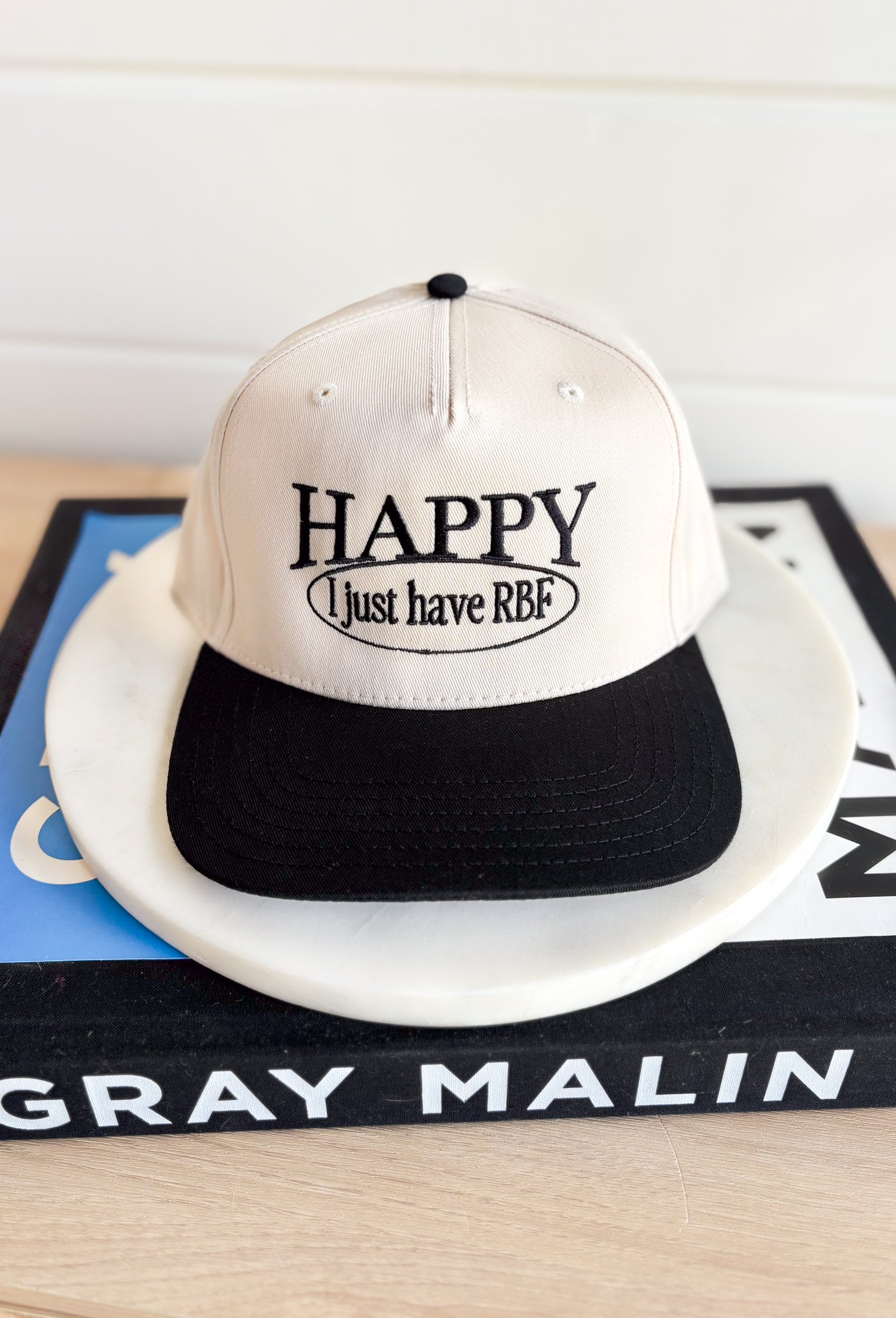 RBF Trucker Hat, black and cream trucker hat with black embroidered text "happy, i just have RBF"