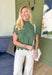 Like A Secret Sweater, short sleeve knit sweater top in fern green, scalloped hemming on the sleeves, high neck, and bottom of the top, black bow detail on the sides of the top 