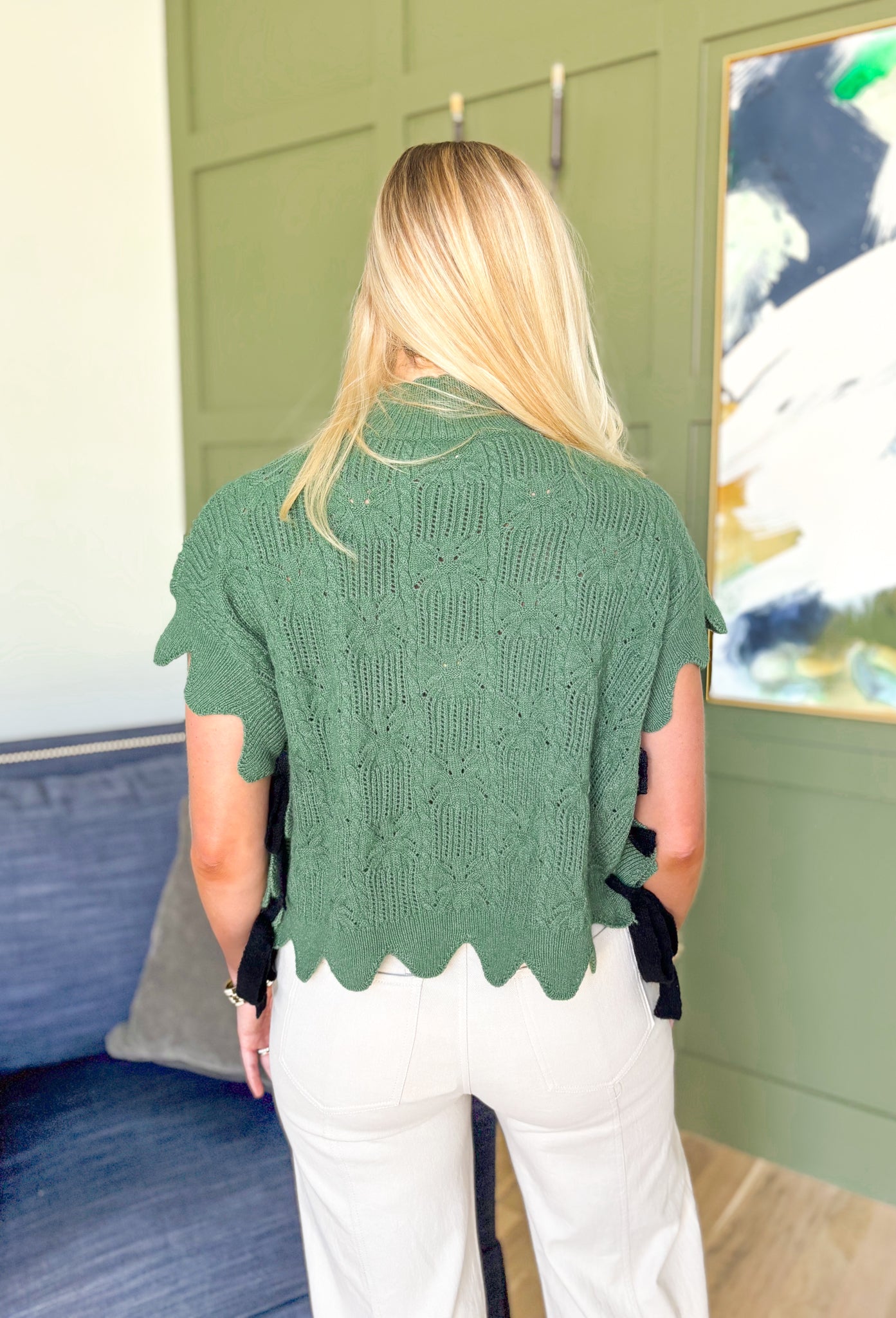 Like A Secret Sweater, short sleeve knit sweater top in fern green, scalloped hemming on the sleeves, high neck, and bottom of the top, black bow detail on the sides of the top 