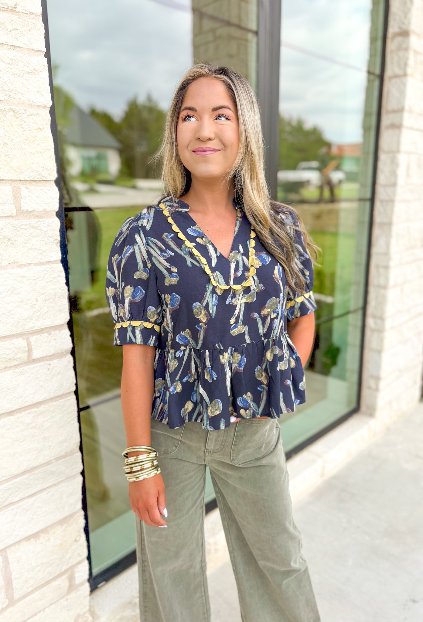 More Than Enough Top, faded navy cropped puff sleeve blouse with v-neck line, abstract tulip detail in sage, blue, and brown, lime scalloping detail on the neck line and on the sleeves