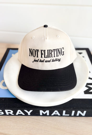 Not Flirting Trucker Hat, black and cream trucker hat with black embroidered text on the front "not flirting just hot and talking"