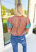 Nothing Has Changed Top, short puff sleeve blouse with v-neck line that has ruffles lining it, abstract print in the colors orange, periwinkle, cream, grey, and turquoise. Turquoise lace details on the puff sleeves 