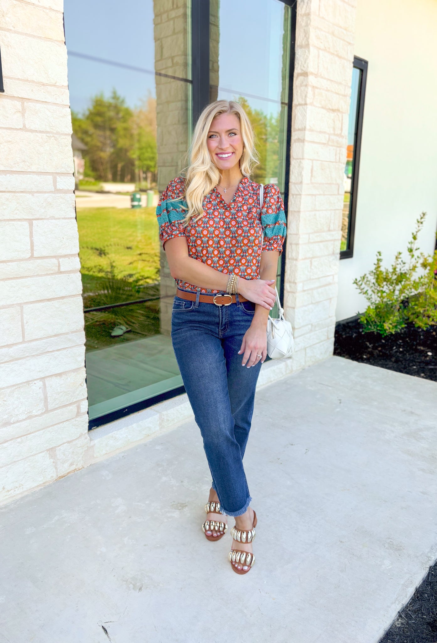 Nothing Has Changed Top, short puff sleeve blouse with v-neck line that has ruffles lining it, abstract print in the colors orange, periwinkle, cream, grey, and turquoise. Turquoise lace details on the puff sleeves 