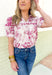 Roaming Rome Floral Blouse, short sleeve plum and off white floral blouse with collar, v-neck, and plum scalloped lace across the chest and around the center of the puff sleeve