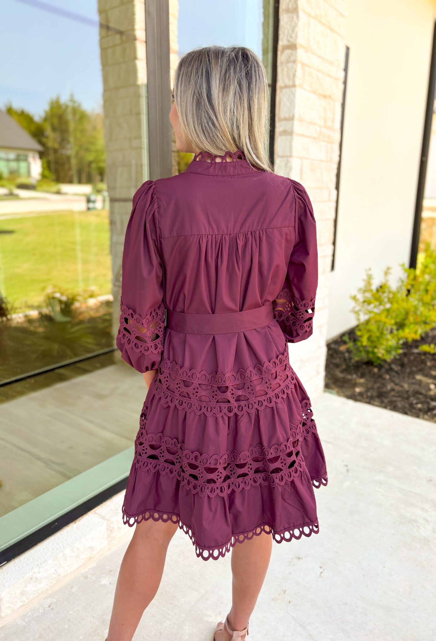 Simply Chic Dress in Merlot, long sleeve pearl button down dress with eyelet lace details on the body, tiers and sleeves of the dress, tie belt detail around the waist, scallop lace detail on the hem of the dress as well as the collar 