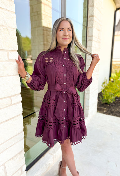 Simply Chic Dress in Merlot, long sleeve pearl button down dress with eyelet lace details on the body, tiers and sleeves of the dress, tie belt detail around the waist, scallop lace detail on the hem of the dress as well as the collar 