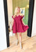 Steal A Kiss Dress, burgundy cap sleeve babydoll mini dress with tiers, pleating across the chest, and wrapped buttons going a quarters length down the front of the dress, v-neck line, pockets 