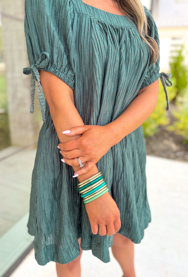 Talk It Out Dress, faded pine green short puff sleeve mini dress with a square neck line, crinkle texture, bow detail on the sleeves 