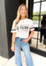 Z SUPPLY Go Team Boyfriend Tee, white loose fit tee with "go team" in black print on the front of the top with taupe and black stripes on the sleeves 