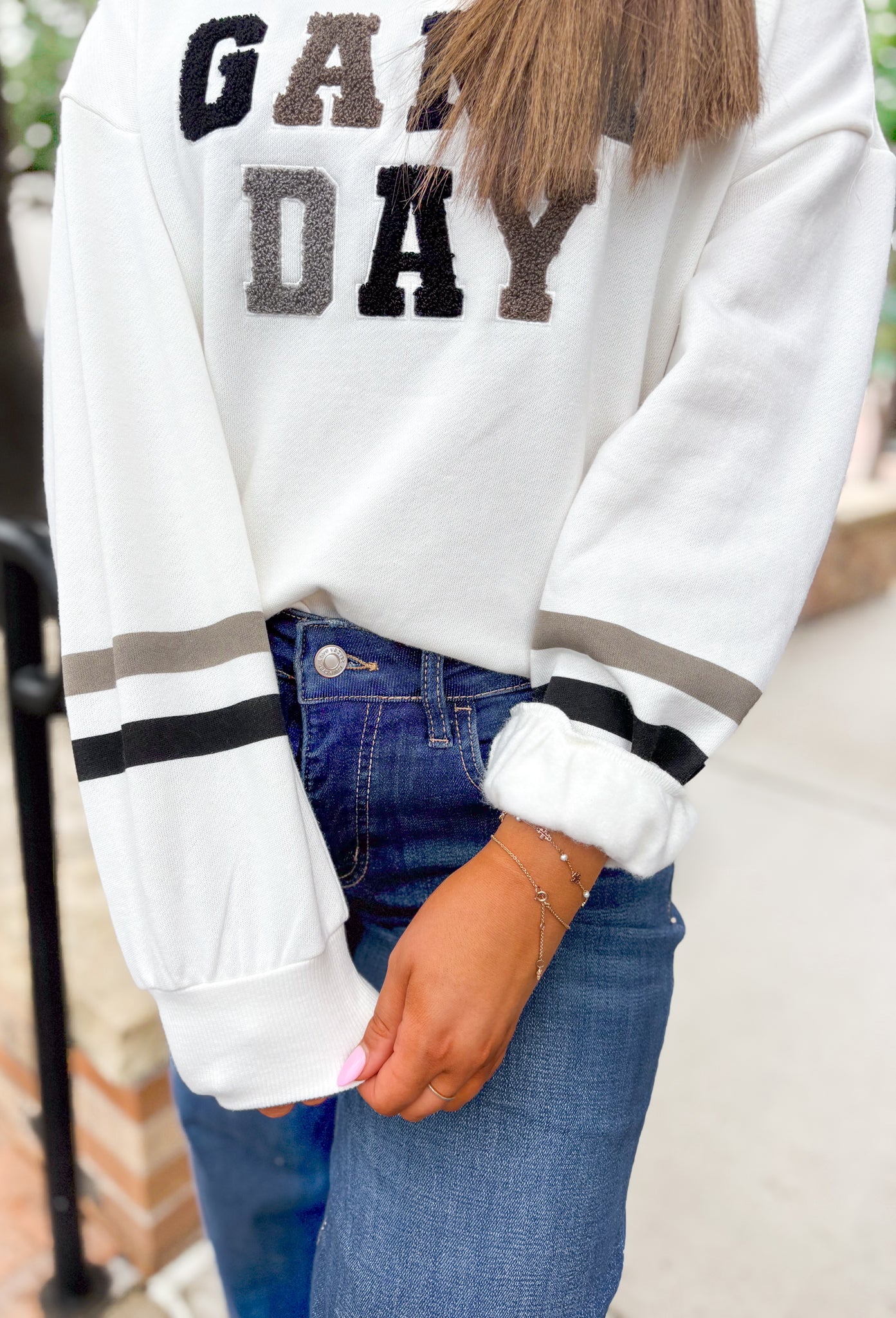 Z SUPPLY Oversized Game Day Sweatshirt in Bone, white crewneck with "game day" spelt out in black, gray, and taupe patches, sleeves have a taupe and black stripe on the wrist 