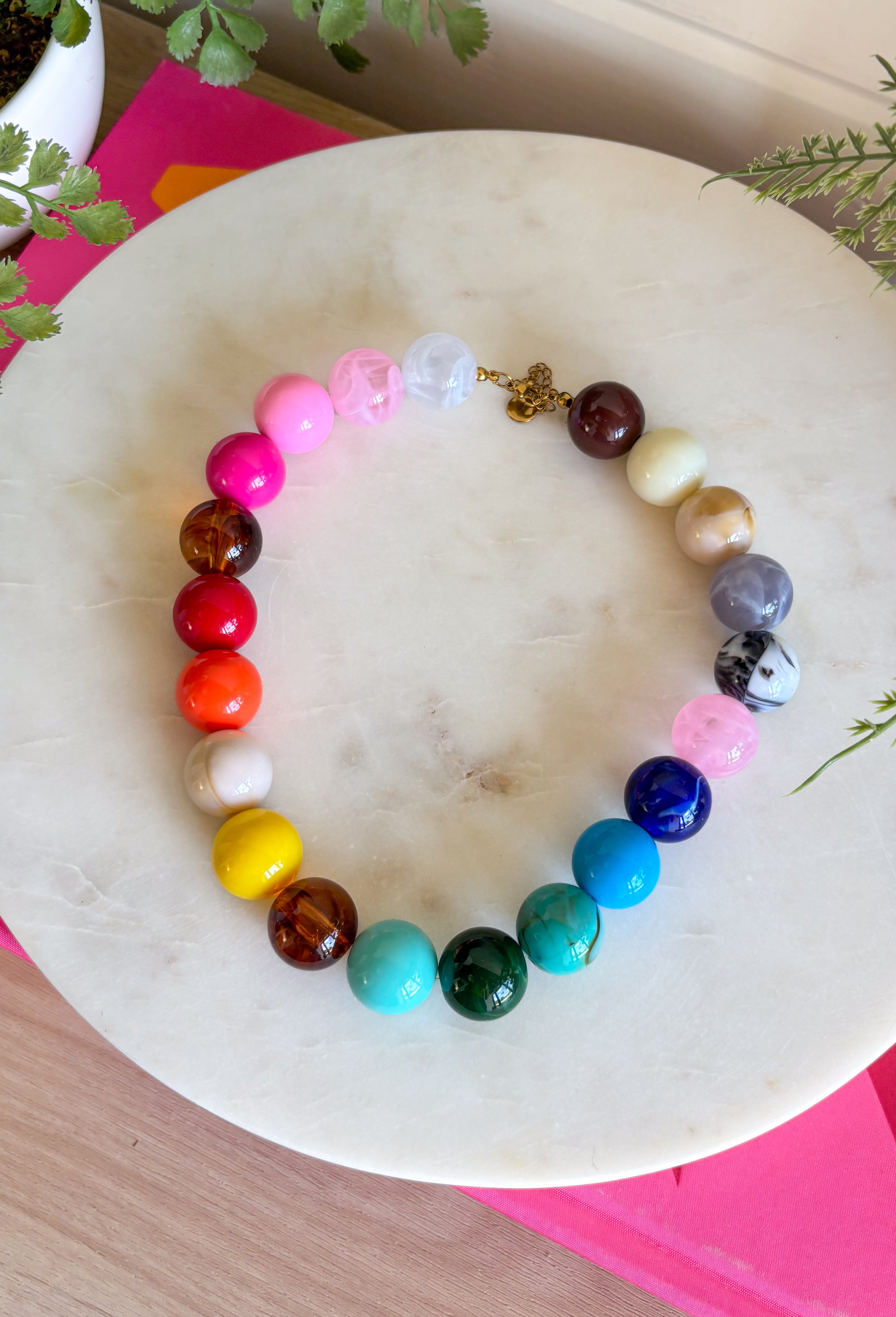 Bring on the sunshine and color! This chunky beaded necklace is the ultimate summer statement piece. Featuring a vibrant mix of colorful beads, it instantly adds a fun, playful touch to any outfit. Whether you're styling it with a simple tank, a breezy sundress, or your favorite vacation look, this necklace does all the heavy lifting. The chunky design keeps it right on trend, while the cheerful colors make it impossible not to smile. 